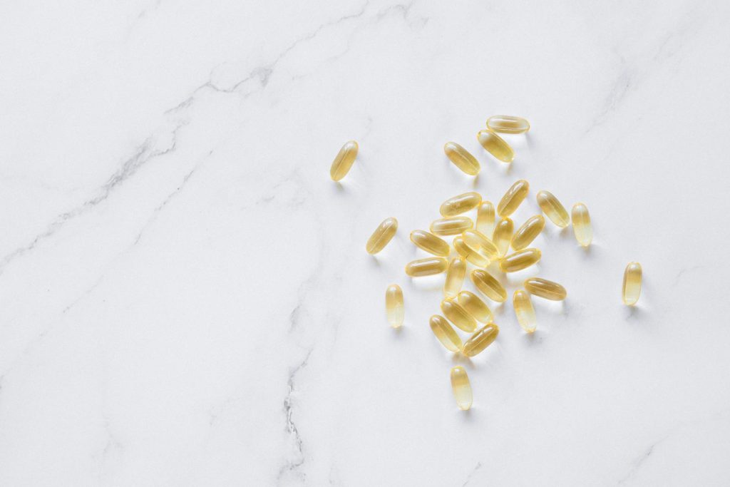 Yellowish Fish Oil Capsules on Marble Surface